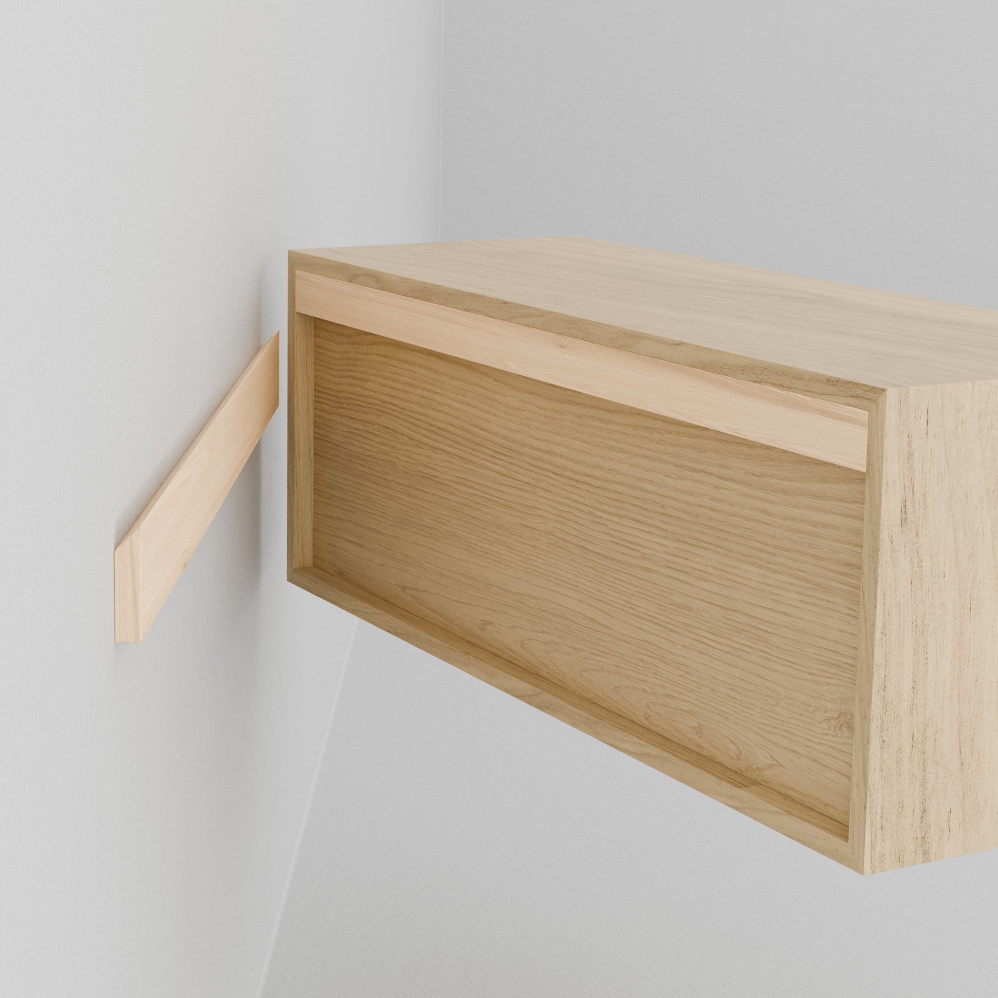 The Krovel Hardwood Double Floating Nightstand features a light wood finish with twin drawers and an open shelf holding two books. A small vase with pink flowers sits on top, set against a plain white wall.
