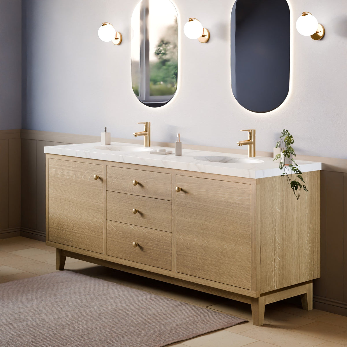 A double-sink bathroom vanity with a light oak wood cabinet, white marble countertop, and gold faucets, shown in a styled bathroom setting with mirrors and wall sconces.#wood_white-oak