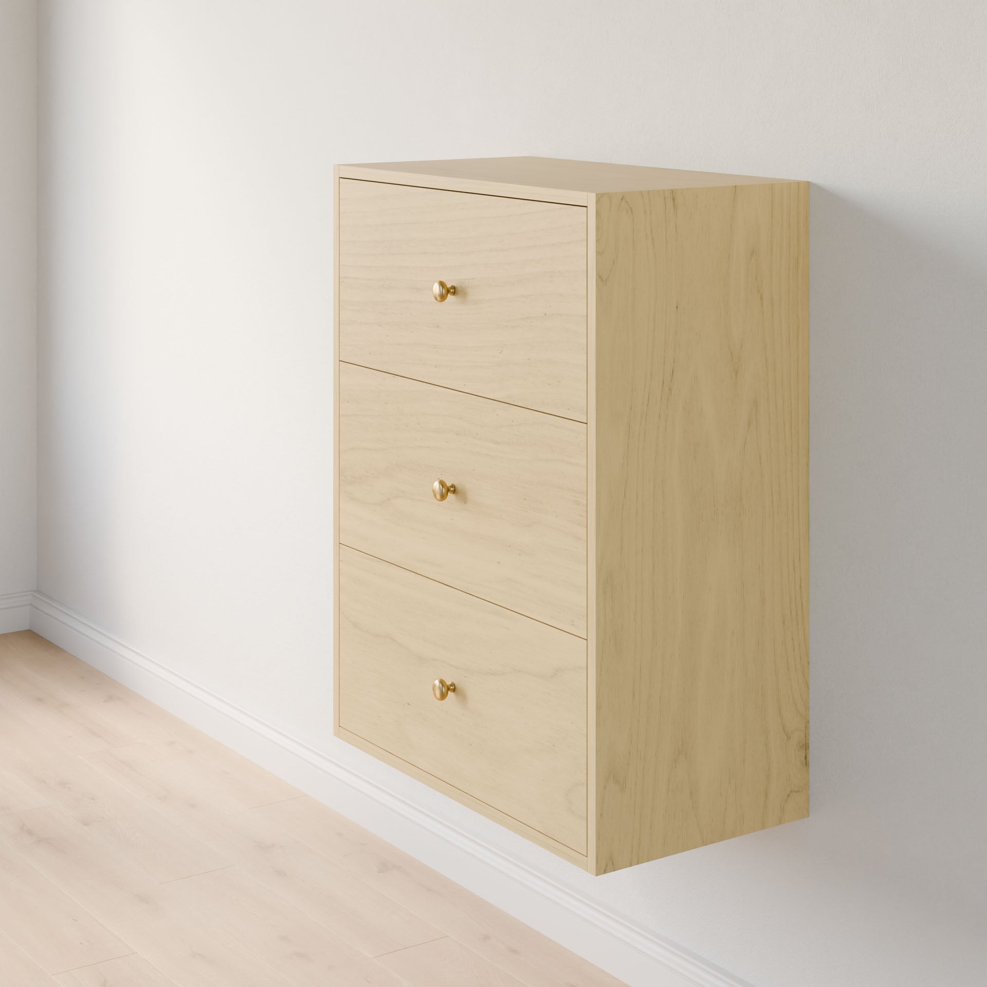 The Maine Made Closet Drawers by Krovel Furniture Co., a light wood wall-mounted cabinet with three drawers and small round golden knobs, is installed on a white wall above a light-colored wooden floor.