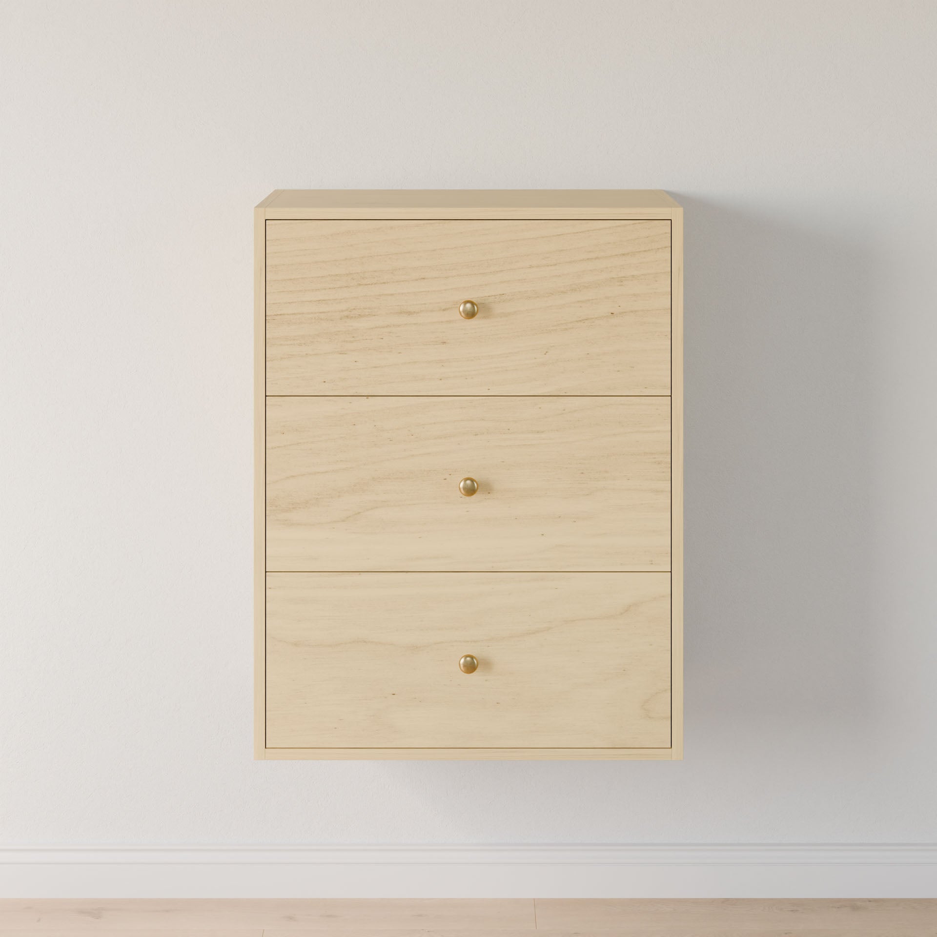 The Maine Made Closet Drawers by Krovel Furniture Co. is a minimalist light wood cabinet with three drawers and round gold knobs, mounted on a white wall above a light floor. Crafted from premium cabinet plywood.
