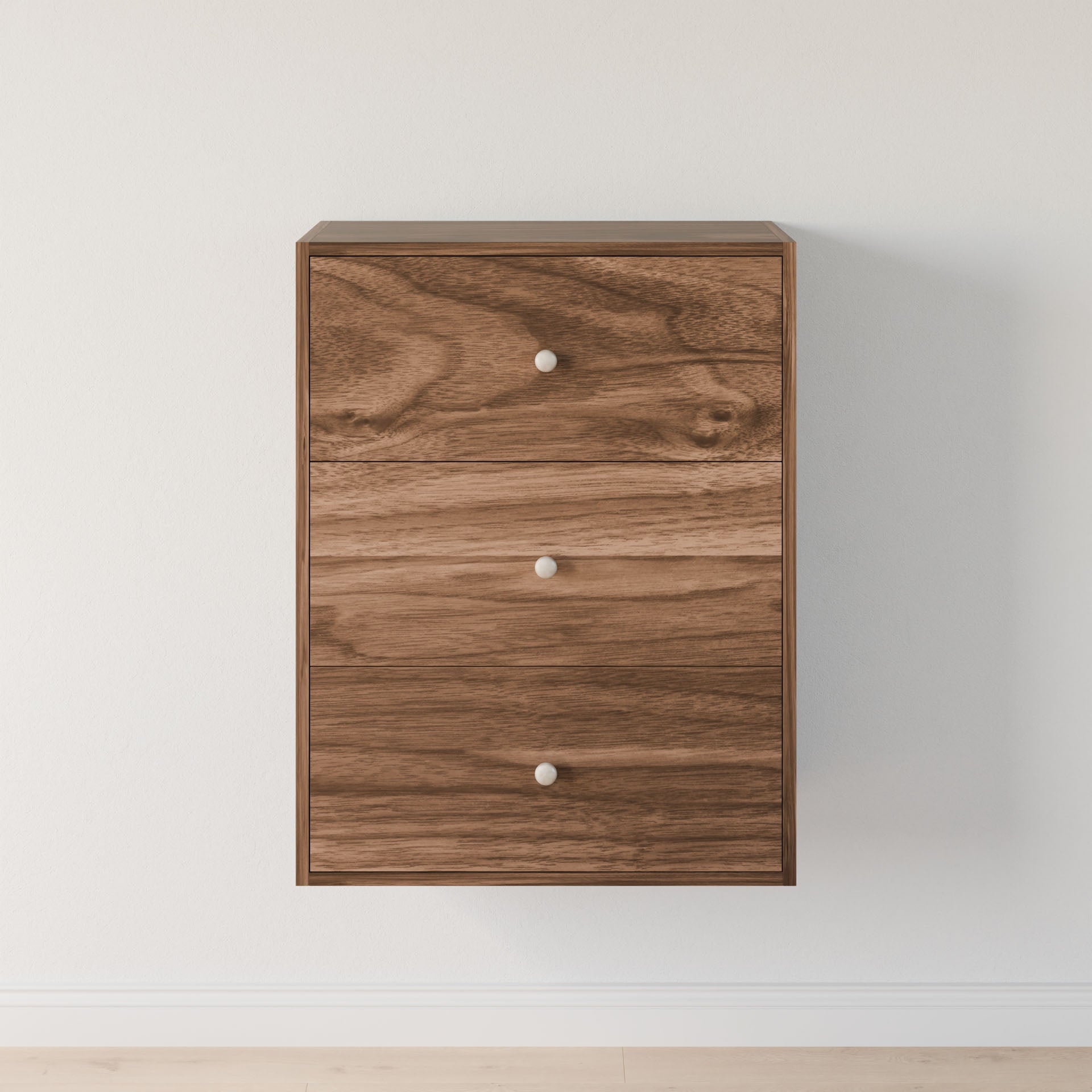 The Maine Made Closet Drawers by Krovel Furniture Co. is a wooden, wall-mounted dresser with three drawers, crafted from premium cabinet plywood and round silver knobs, set against a plain white wall and light wood floor.