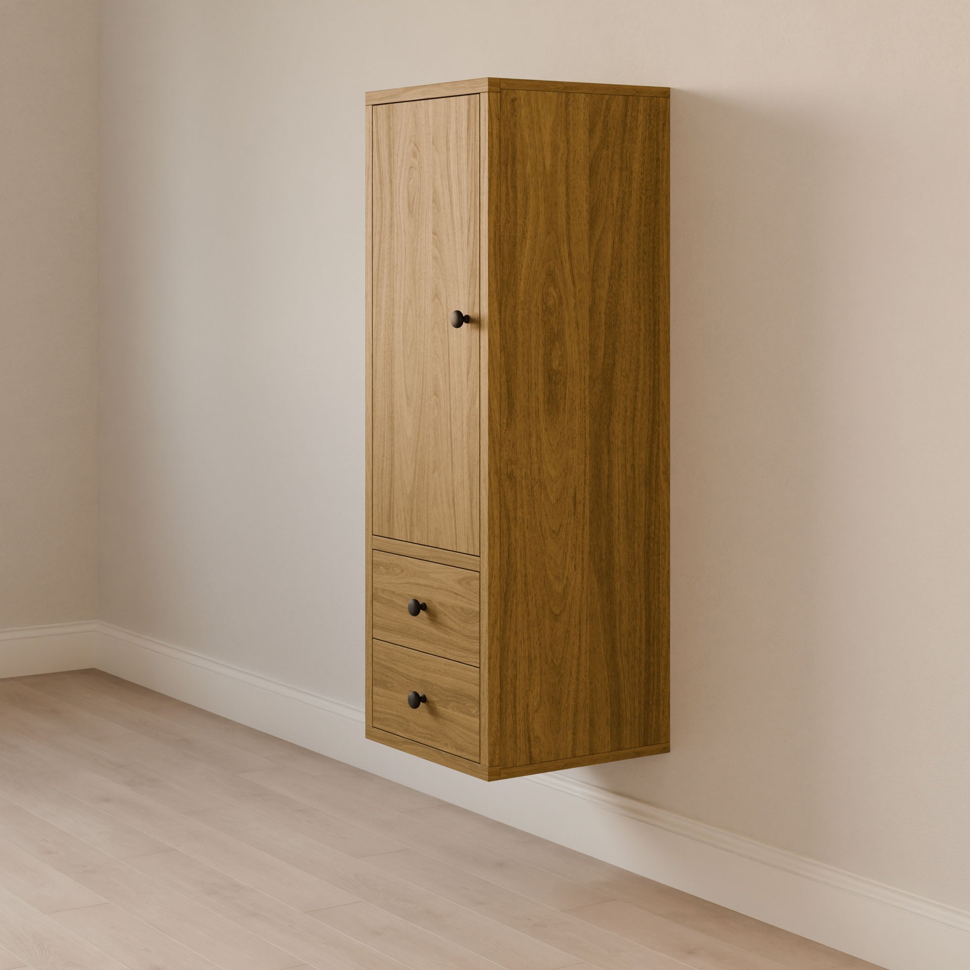 The Maine Made Double Drawer Linen Cabinet by Krovel Furniture Co. features a solid hardwood build, vertical top door, two drawers with black knobs, and is mounted on a light-colored wall above a light wood floor.