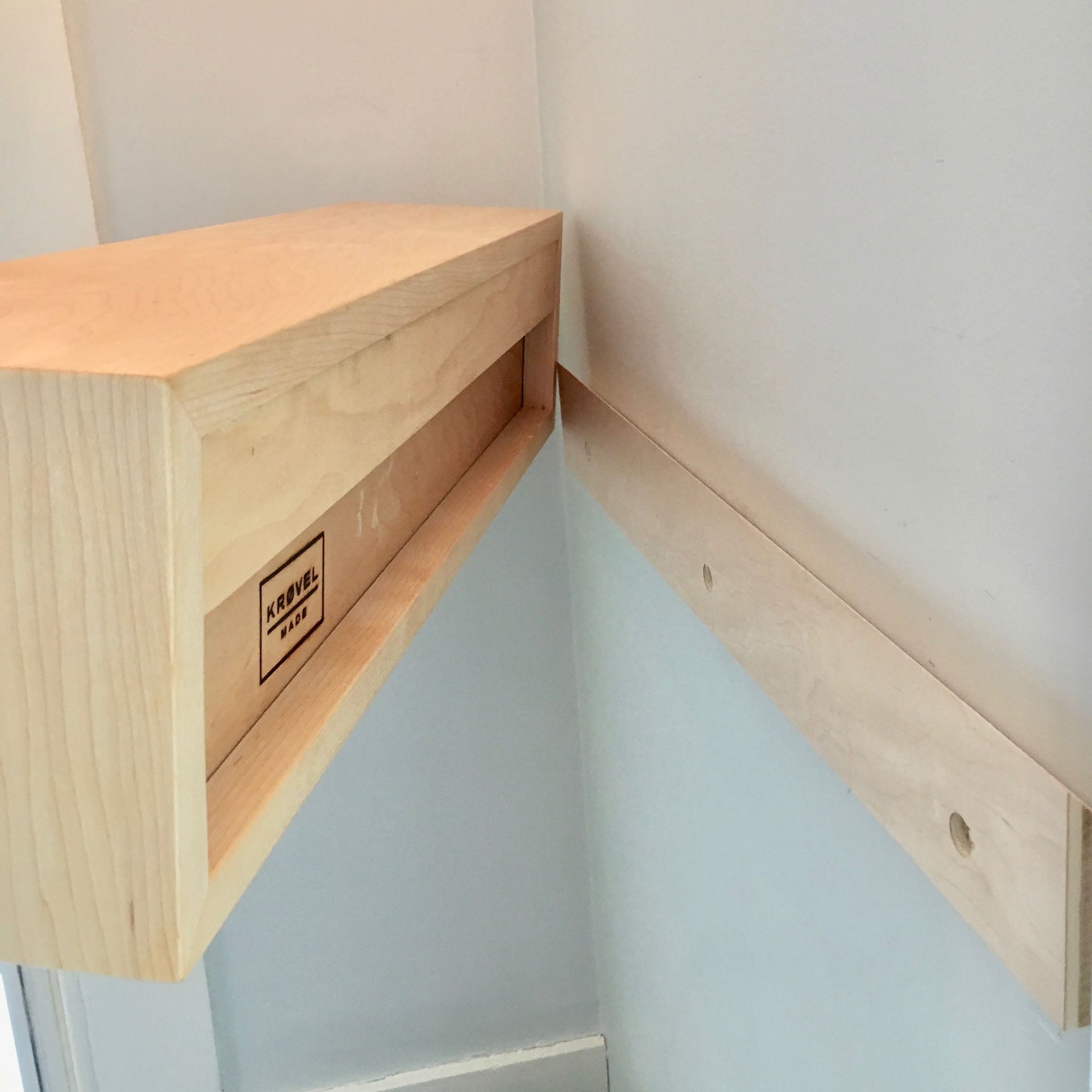 The Krovel Hardwood Entryway Organizer is a handmade floating shelf mounted with a matching wooden wall bracket featuring two screw holes for secure installation.