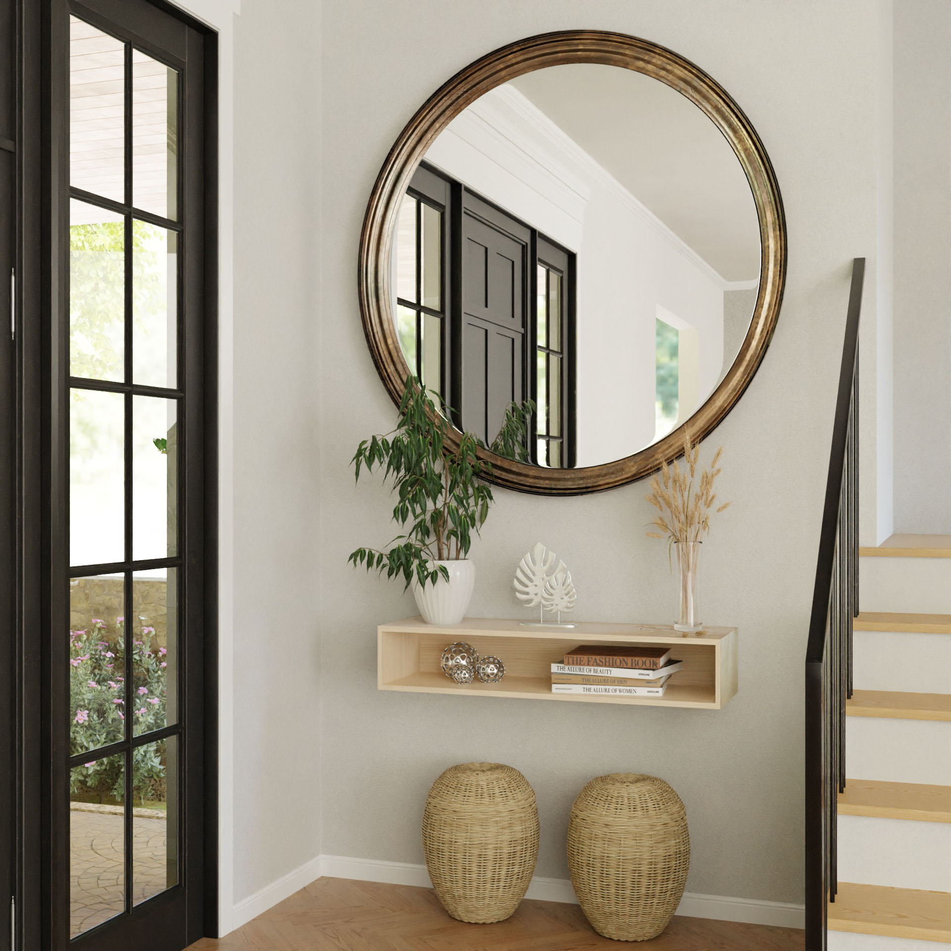 A modern entryway features a large round mirror above the Krovel Hardwood Floating Console Table, styled with plants, books, and decor. Two woven baskets rest on the floor near stairs and black-framed glass doors; neutral walls and natural light complete the scene.