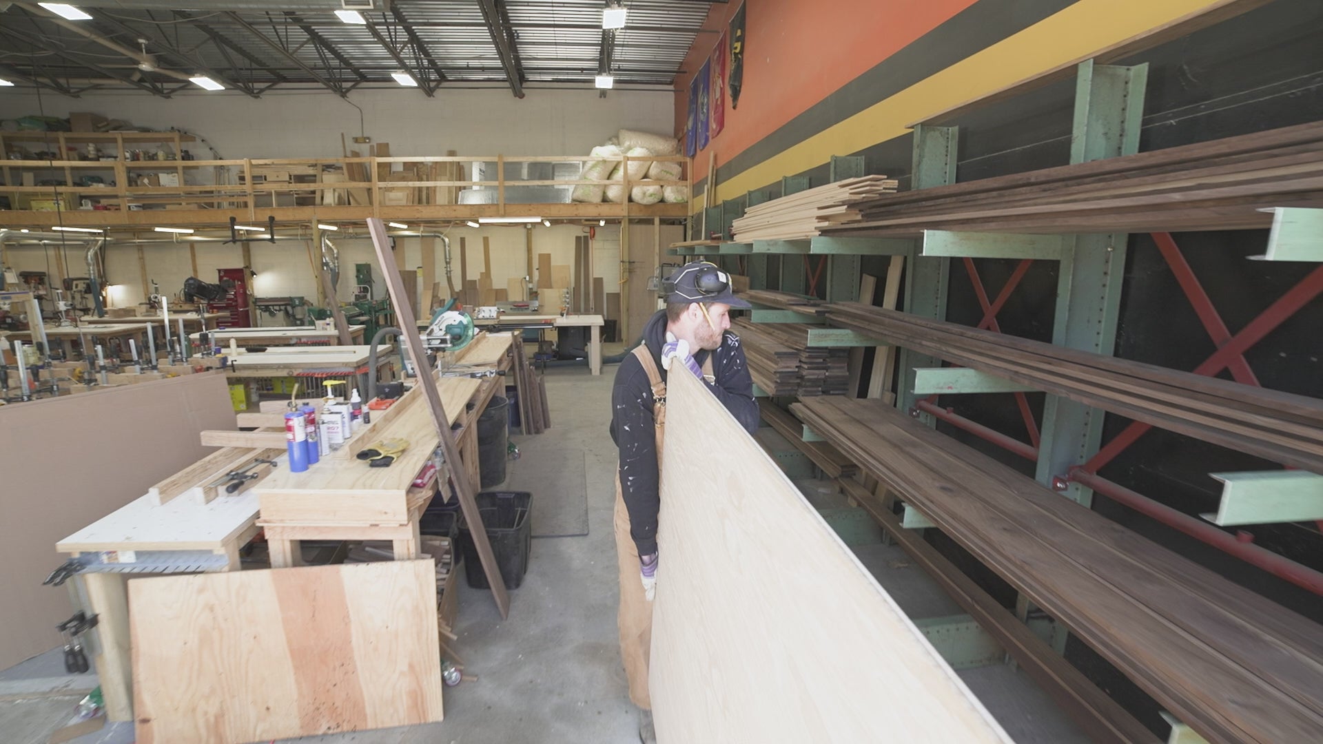 Load video: A man carrying a large piece of hardwood for making Krovel Furniture
