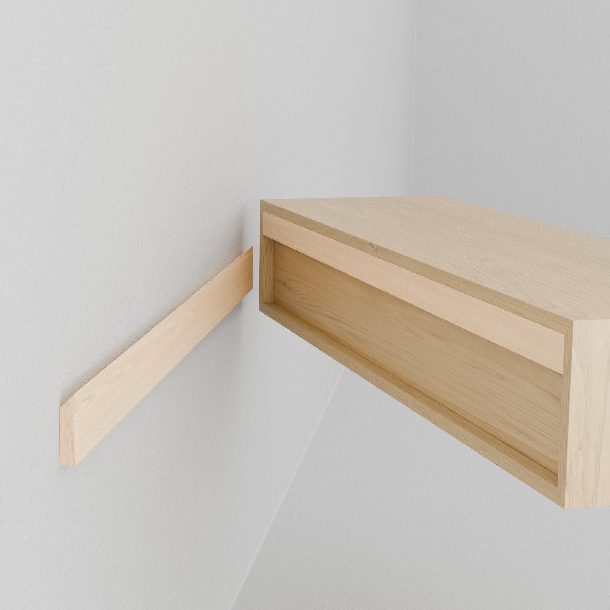A close-up of the Krovel Hardwood Floating Desk being installed on a white wall, with one support bracket visible and the floating desk shelf partially resting on it.