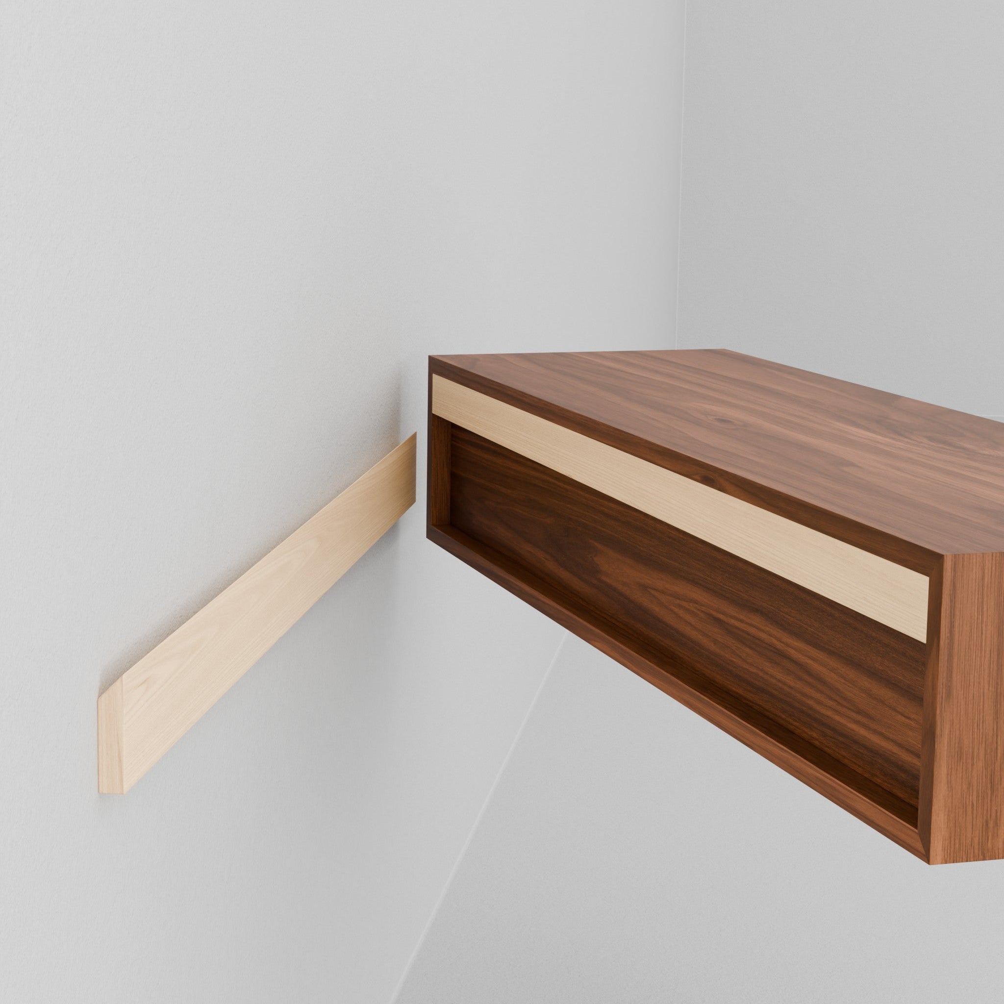A person installs the Krovel Hardwood Floating Desk onto a wooden support cleat mounted on a white wall, aligning the desk for a sturdy, stylish workspace—just like setting up other wall-mounted desks.