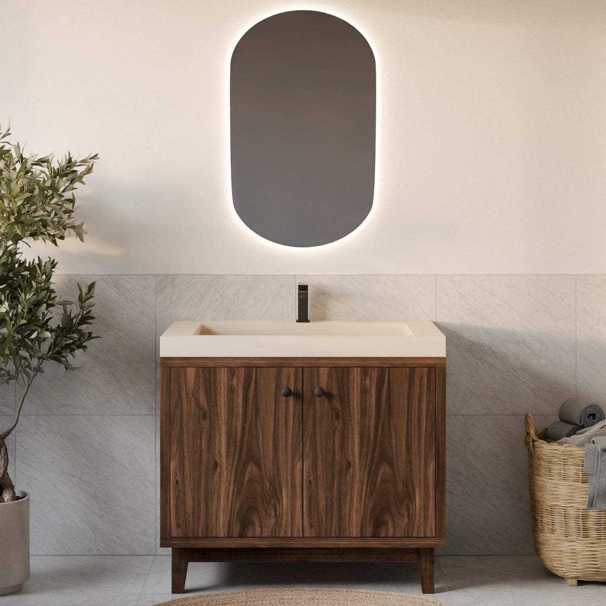 A modern bathroom vanity with a dark wood cabinet, a cream-colored countertop and basin, a matte black faucet, and an oval backlit mirror mounted on a light beige wall. The scene is styled with a potted plant on the left and a woven basket on the right.