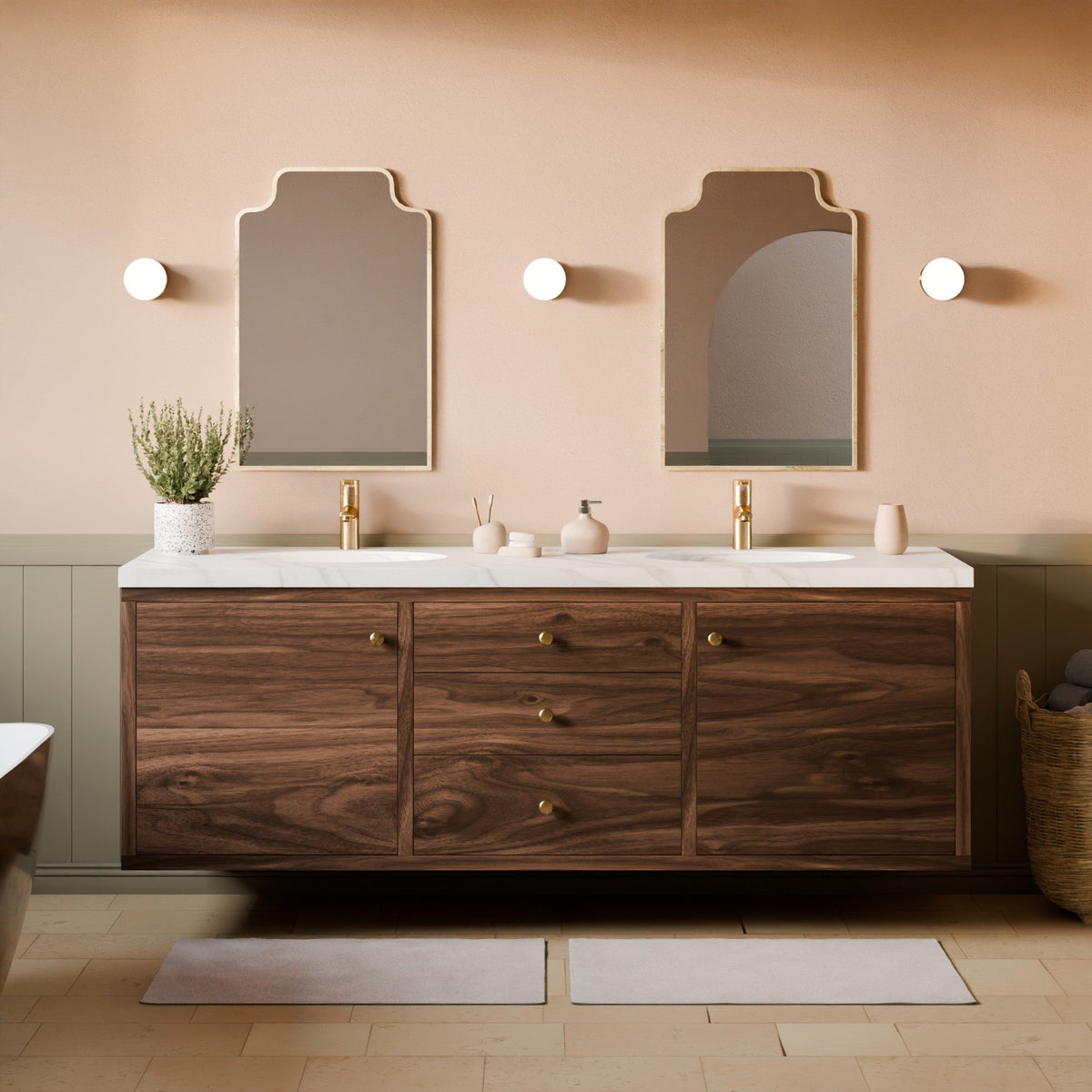 A floating double-sink bathroom vanity with a dark wood cabinet, white marble tops, and gold faucets, set against a warm beige wall with two arched mirrors and wall sconces.