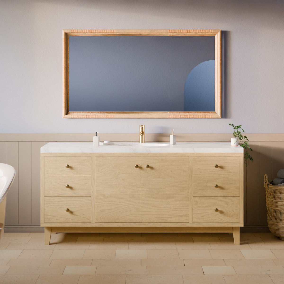 A light natural wood bathroom vanity with a white marble countertop, integrated sink, and a matching rectangular mirror with a natural wood frame, set against a gray wall with wainscoting.