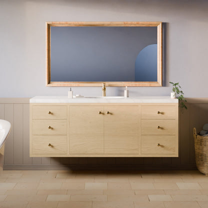 A light natural wood double-sink bathroom vanity with brass hardware, a white countertop, and a large matching wood-framed mirror, shown in a styled bathroom setting.