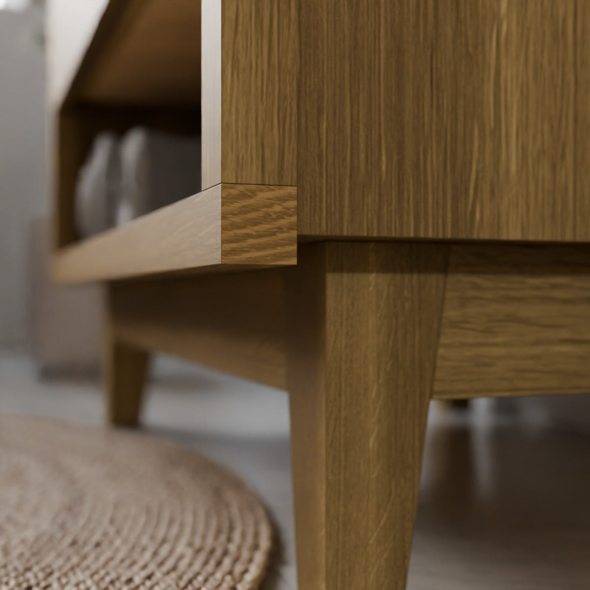 Close-up of a Krovel Furniture Co. wooden furniture piece, showing the corner joint and leg with a visible woven rug on the floor in the foreground.