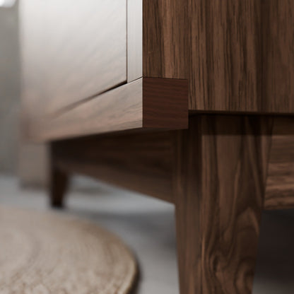Close-up of a dark brown wooden furniture piece, showing the corner joint and leg with a light-colored wall and floor in the background.