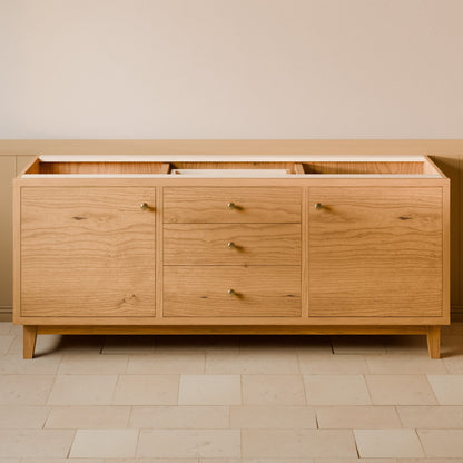 A mid-century modern oak wood sideboard cabinet with three drawers and three cabinet doors, featuring small brass knobs and tapered wooden legs, set against a neutral beige wall and tiled floor.