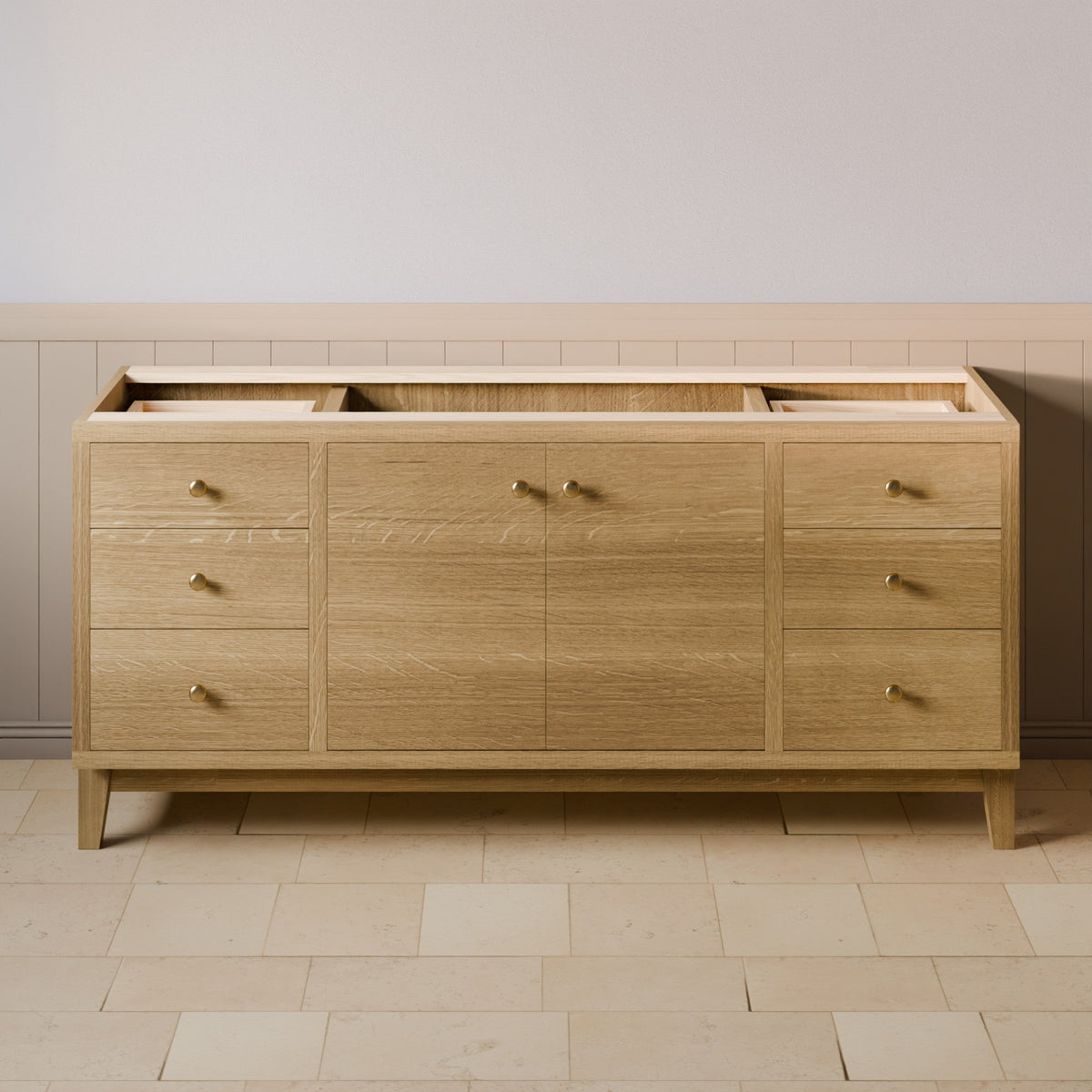 A mid-century modern light oak wood credenza or sideboard with brass handles, shown in a staged room setting with a tiled floor and paneled wall.
