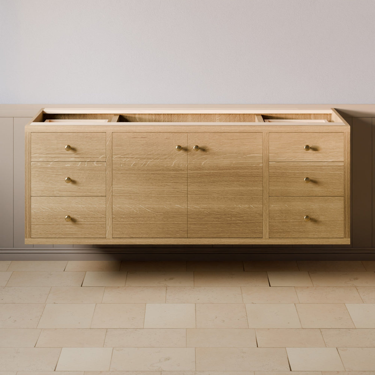A light oak wood wall-mounted vanity cabinet with multiple drawers and doors, featuring small brass handles, shown against a neutral beige wall and tiled floor.