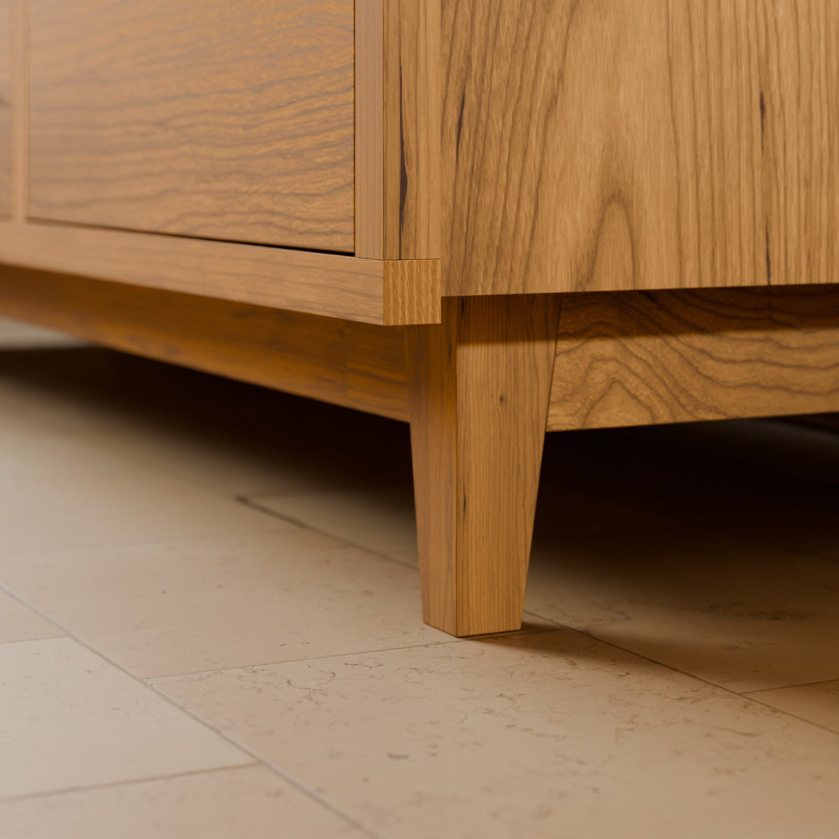 Close-up of a mid-century modern wooden cabinet with a warm oak finish, showing the corner joint and tapered legs on a light beige tiled floor.#wood_cherry