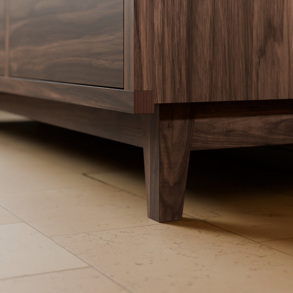 Close-up of a dark wood cabinet or sideboard with a visible leg, shown in a real interior setting on a light stone tile floor.