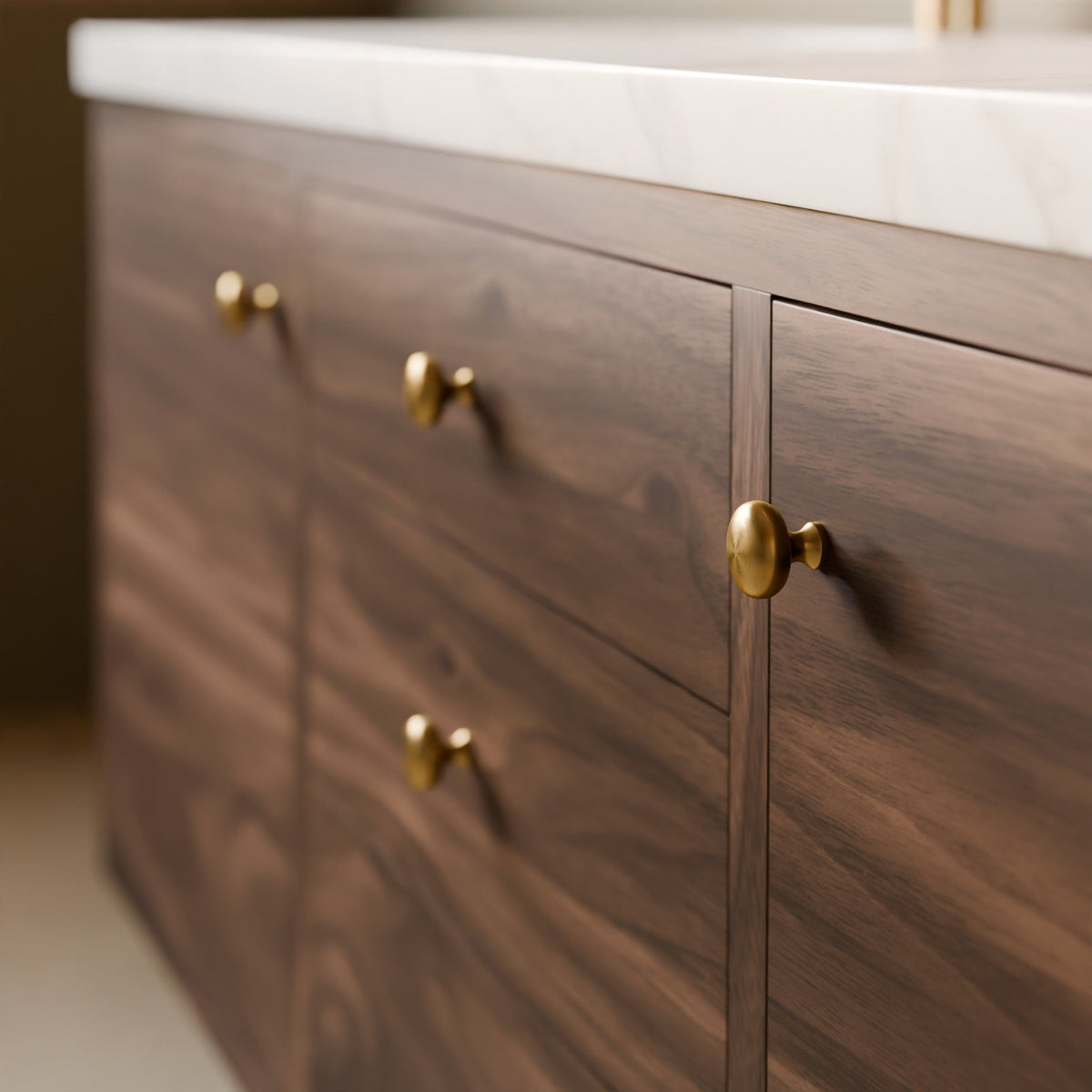Close-up of a dark wood vanity cabinet with brass round knobs and a white stone countertop in a bathroom setting.#wood_walnut