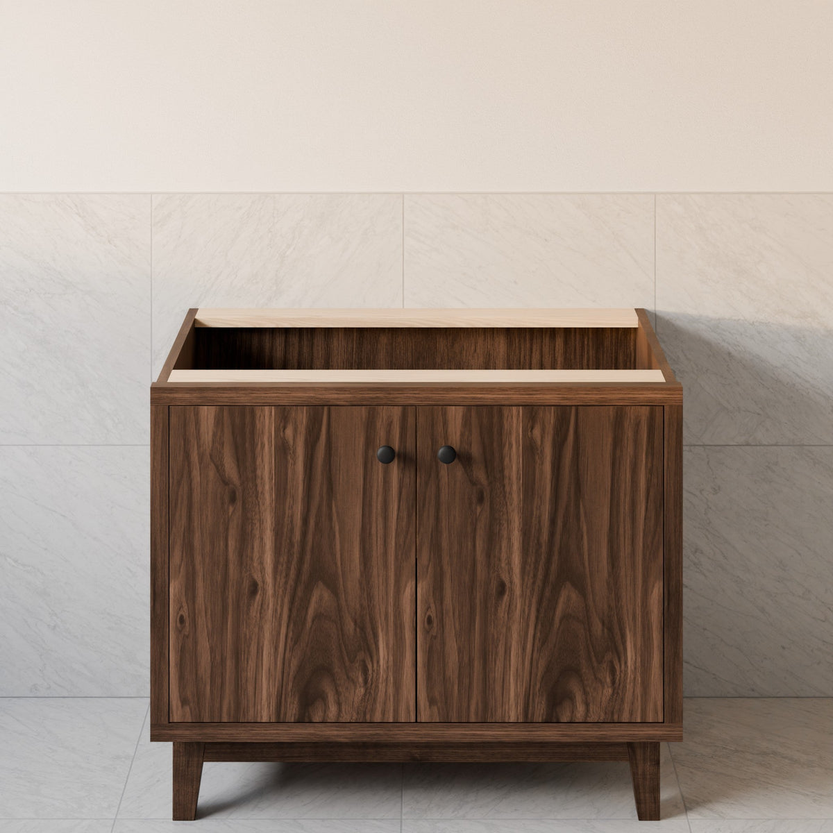 A mid-century modern wooden cabinet with a dark walnut finish, featuring two doors with round black knobs, a light wood top, and tapered legs, set against a light gray tiled wall.