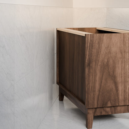 A modern rectangular wooden vanity or cabinet shown in a bathroom setting with light marble tile walls and floor.