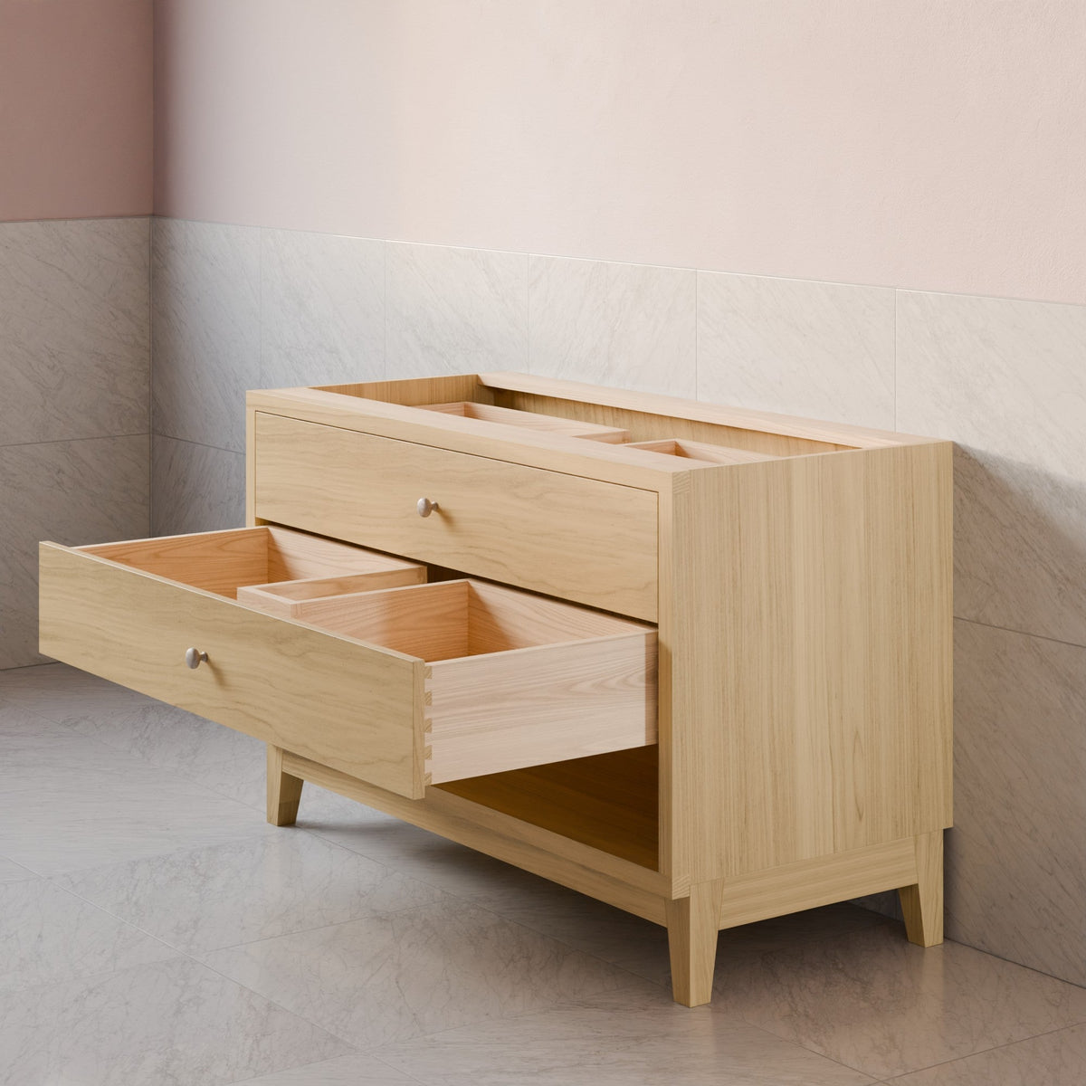 A light natural wood storage cabinet with two open drawers and a top organizer tray, set against a two-tone beige and gray tiled wall.