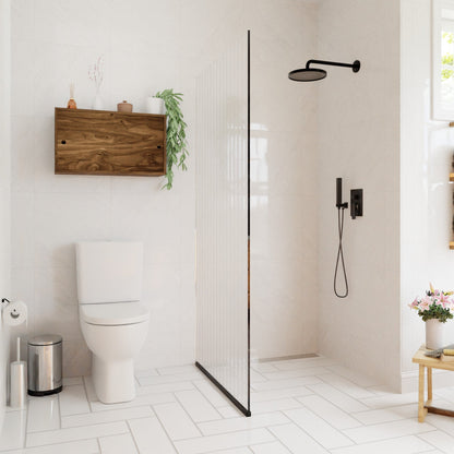 Modern bathroom with white tile, a walk-in shower behind a glass partition, and a Krovel Hardwood Cupboard Shelf above the toilet displaying plants. A small table with flowers sits by the window, adding charm to the bright space.