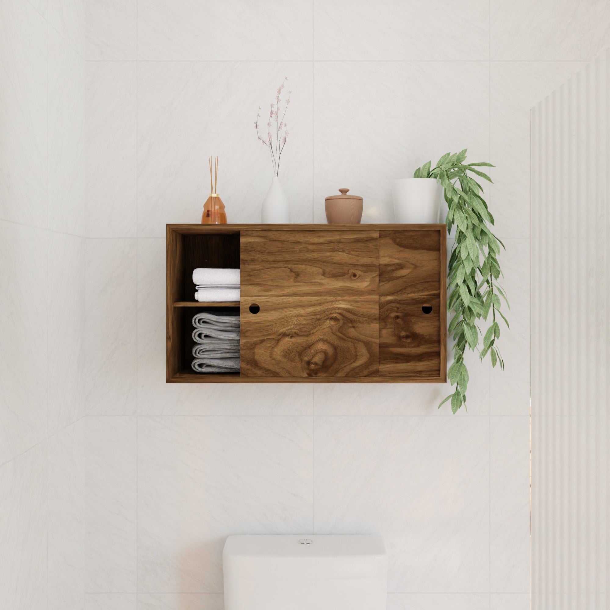 The Krovel Hardwood Cupboard Shelf is mounted above a toilet, storing rolled towels, stacked white towels, ceramic containers, a small vase with dried flowers, and a trailing green plant.