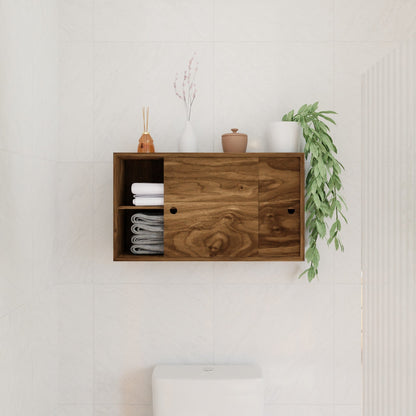 The Krovel Hardwood Cupboard Shelf is mounted above a toilet, storing rolled towels, stacked white towels, ceramic containers, a small vase with dried flowers, and a trailing green plant.