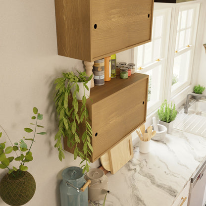 A marble kitchen counter holds utensils, a cutting board, and a teapot. Nearby, the Krovel Hardwood Cupboard Shelf adds warmth alongside potted plants. Sunlight streams in from large windows above the sink.