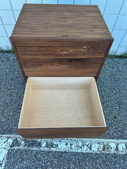 A 3 Drawer Dresser in Walnut by Krovel Furniture Co. is pictured outdoors on pavement; the lower drawer is fully open, revealing a light wood interior finished with a zero-VOC finish, while the upper drawers remain closed.