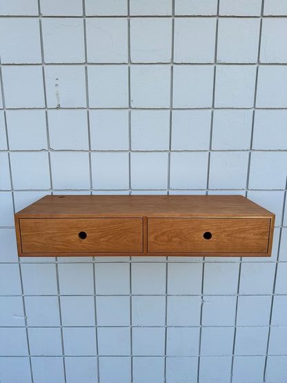 A Cherry Desk 40″ – SAMPLE by Krovel Furniture Co., featuring two solid Maple drawers with round hole handles, mounted on a white tiled wall.