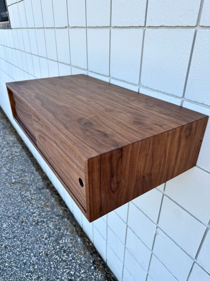The Custom Walnut Media Table - SECOND by Krovel Furniture Co. features a rich walnut finish that adds warmth and sophistication, seamlessly blending into any modern space with its sleek, floating design.