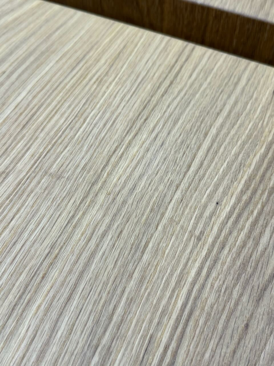 Close-up of a light-colored wooden surface crafted from solid White Oak, with visible grain patterns and a dark horizontal seam near the top—characteristic of Krovel Furniture Co. PAIR (2) White Oak Floating Nightstands - SECONDS.