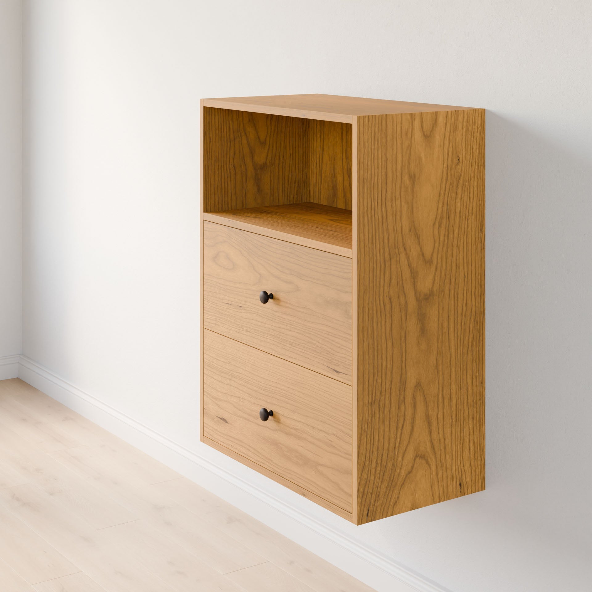 The Krovel Furniture Co. Maine Made Closet Drawers is a wooden wall-mounted cabinet with an open upper shelf and two drawers featuring small round black knobs, shown fixed to a white wall above a light wood floor.