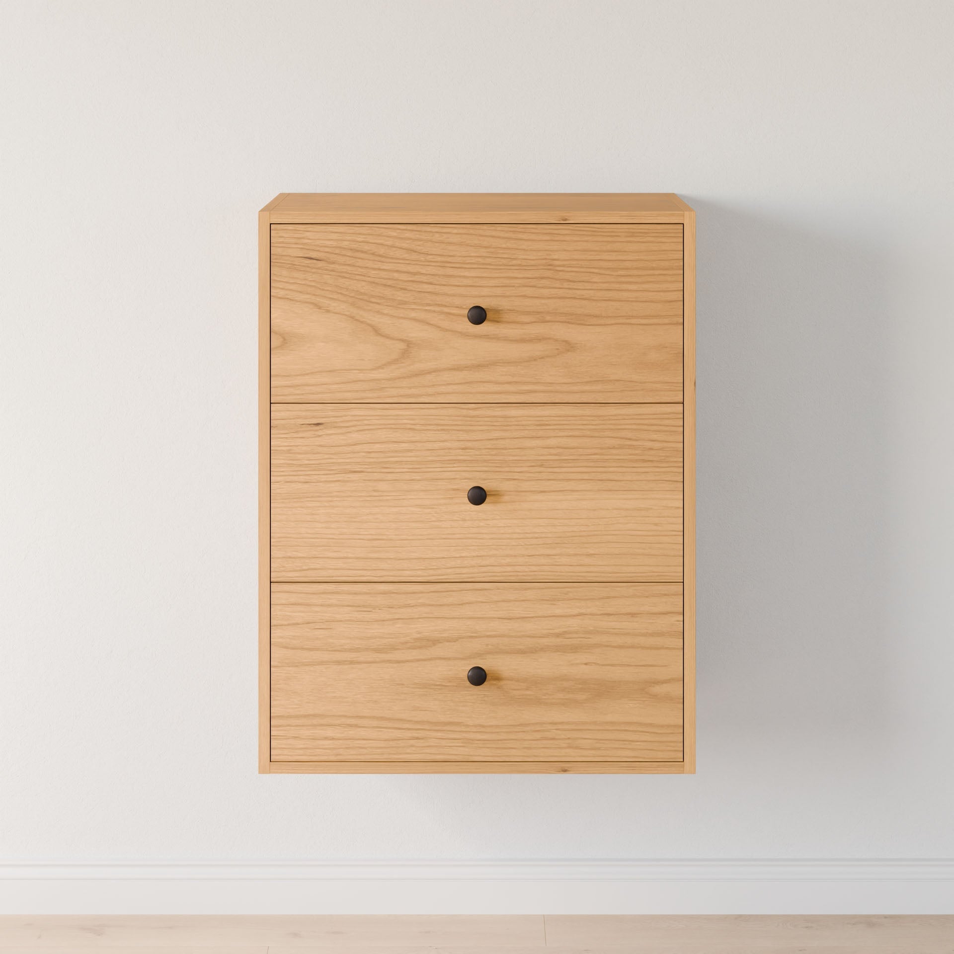 The Maine Made Closet Drawers by Krovel Furniture Co. is a minimalist modular shelf system with three drawers, crafted from quality cabinet plywood, featuring round black knobs, ideal for white-walled, light wood-floored spaces.