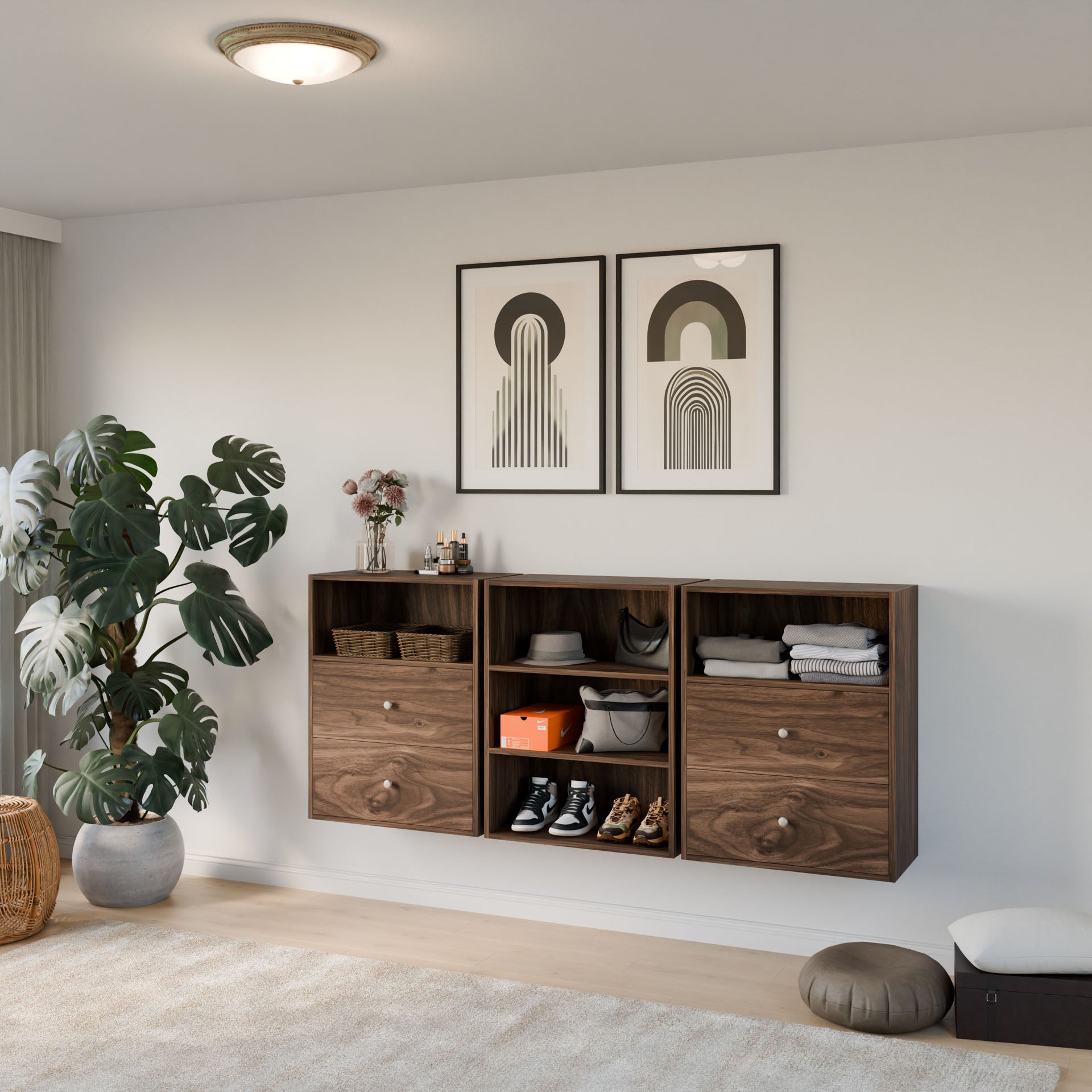 A modern living space features three Krovel Furniture Co. Maine Made Closet Drawers for shoes, clothes, and accessories. Two abstract artworks hang above, while a large potted plant sits on the floor to the left.