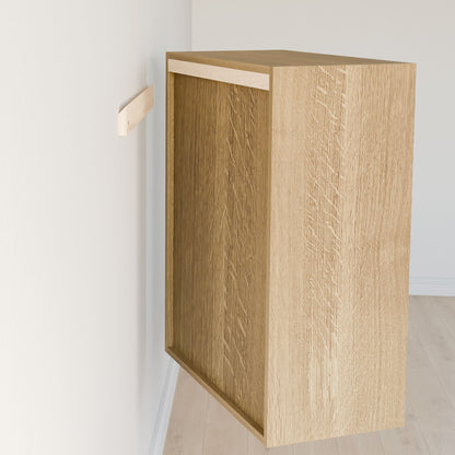A Maine Made Closet Shelf from Krovel Furniture Co. is mounted on a white wall beside a large premium-grade cabinet with an unfinished back, set in a room with light wood flooring and plain white walls.