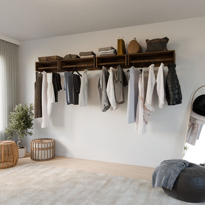 A minimalist closet featuring Krovel Furniture Co.'s Maine Made Closet Hanger, open wooden shelves of premium plywood, neutral clothes, bags above, a floor mirror, pouf, woven basket, plant, and soft natural light from a window.