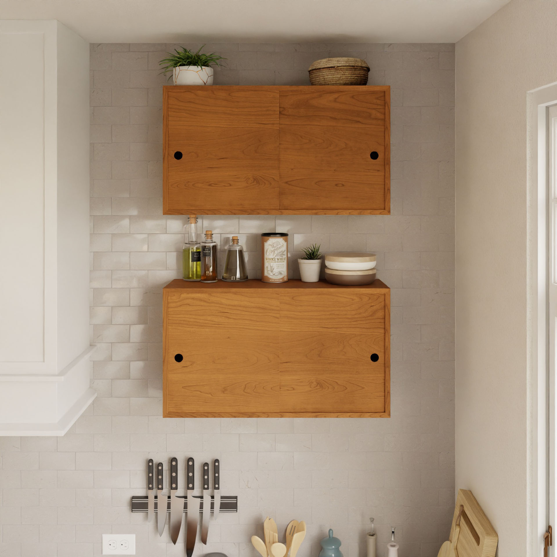 In a cozy kitchen, two Krovel "Cupboard with Shelf in Cherry" units float on the light tiled wall, showcasing small plants and kitchen items. Below, six knives magnetically attach to the backsplash. A window on the right invites natural light to enhance this chic setup.