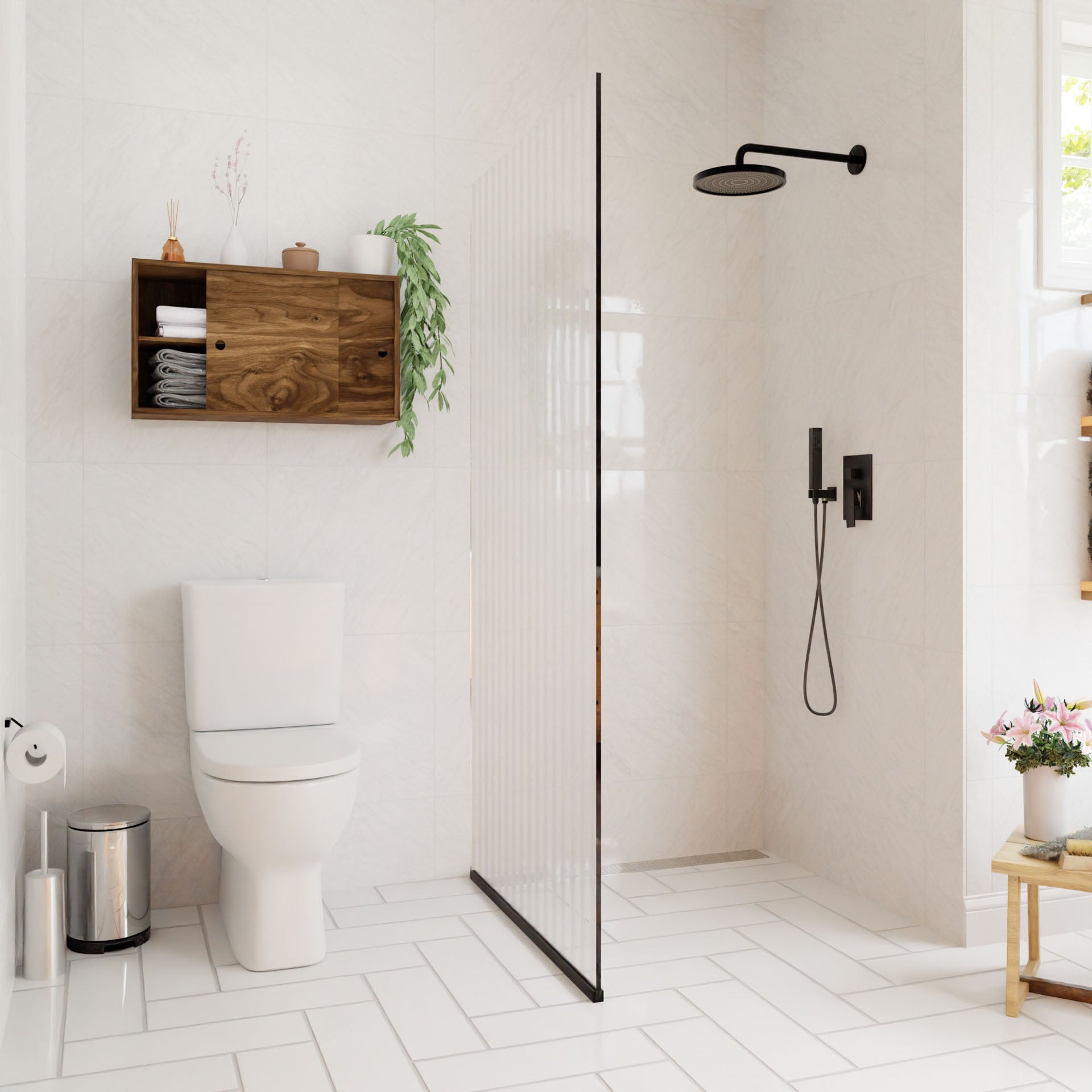 A modern bathroom with white tiles includes a walk-in shower with a black rain showerhead. A Krovel Cupboard with Shelf in Walnut elegantly floats above the white toilet, complementing the wooden shelf displaying towels and plants. Natural light streams through a window decorated with flowers.