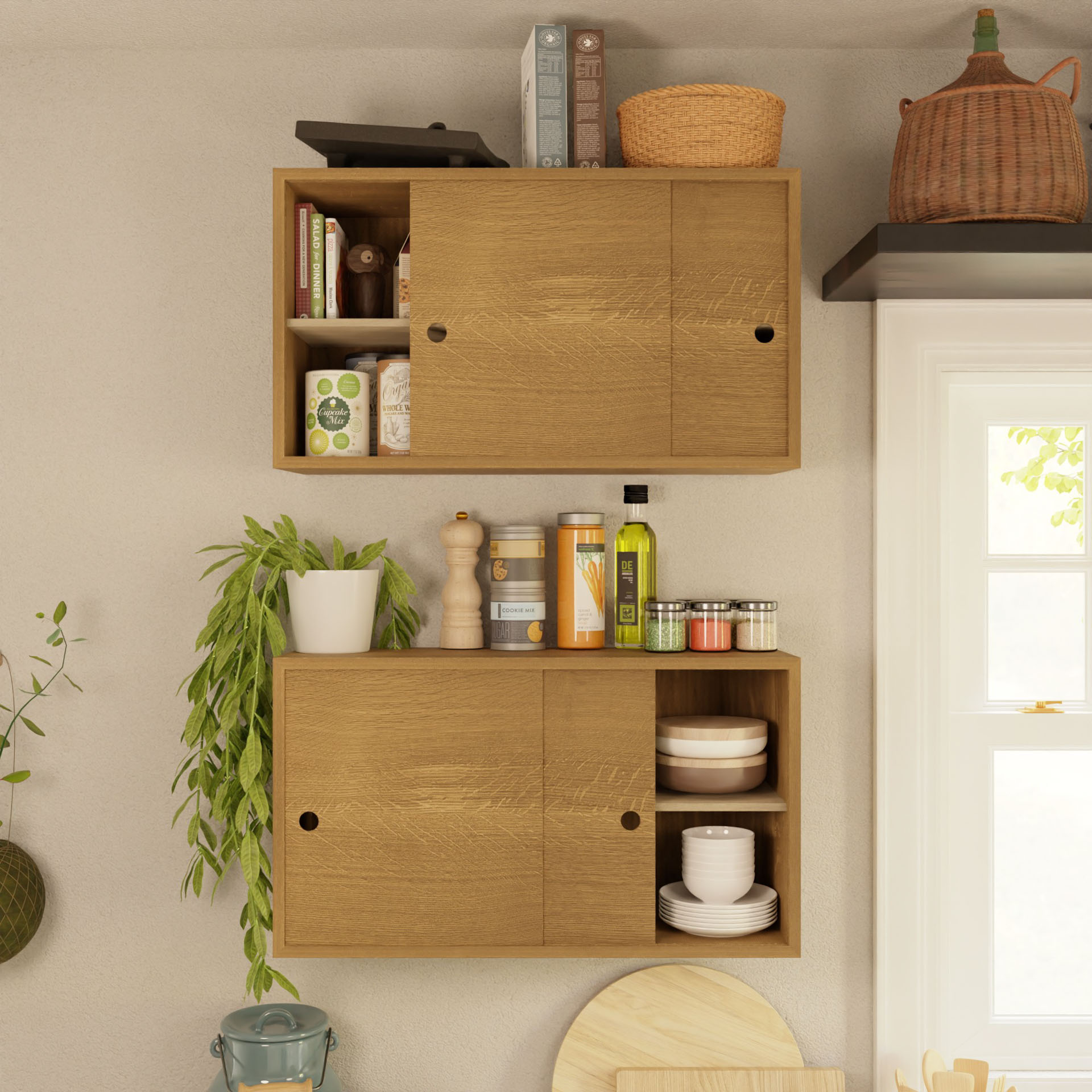 Two Krovel Cupboards with Shelf in White Oak showcase kitchen essentials. The top holds books, a pot, and canned goods; the lower floating cupboard stores plates and jars. Nearby, a hanging plant adds greenery beside a window and wicker basket.