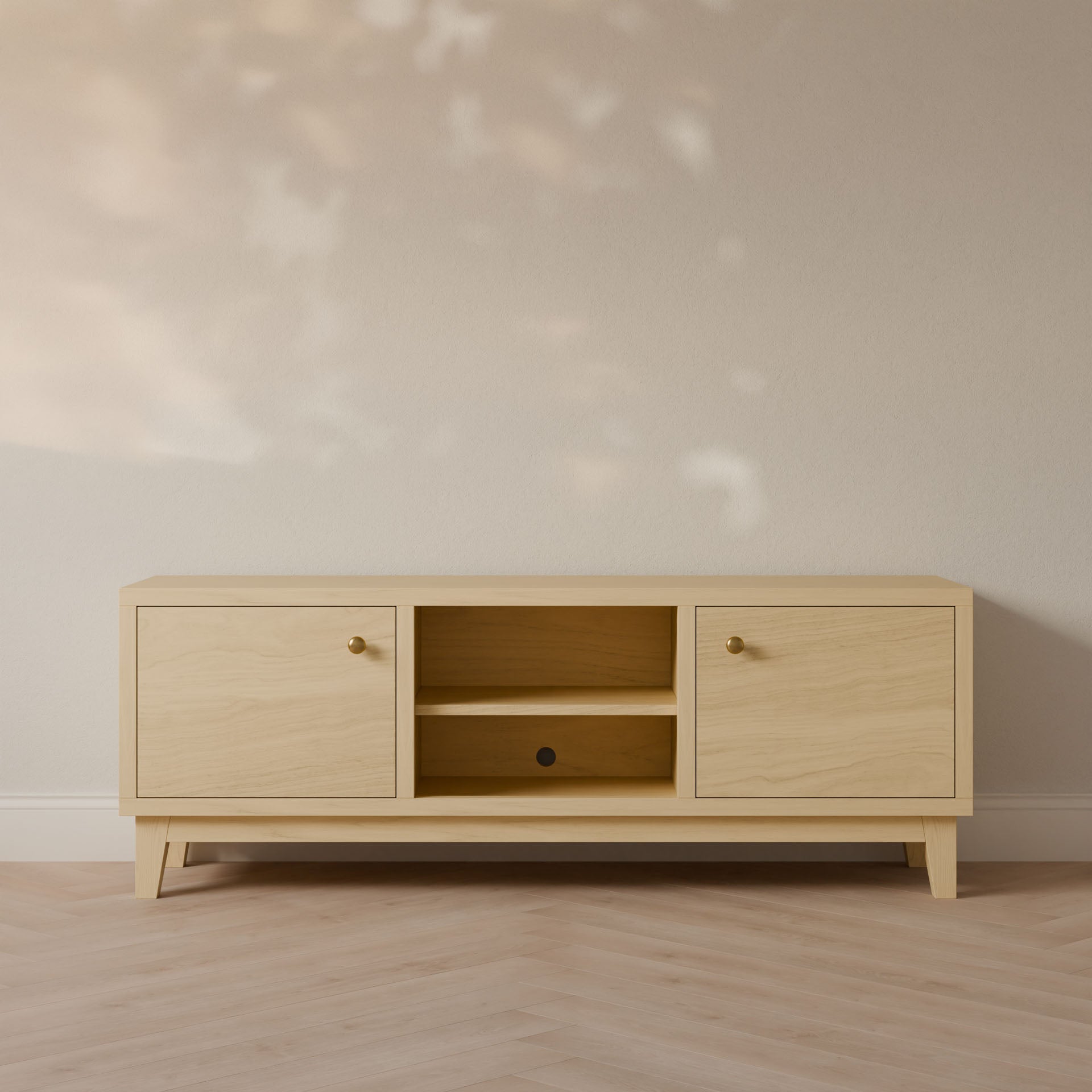 The Double Door, Open Shelf Media Cabinet in Maple by Krovel Furniture Co. features a minimalist design with a light hardwood veneer finish, round knob cabinets, and an open center shelf. Its showcased against a neutral wall with a herringbone-patterned wooden floor.