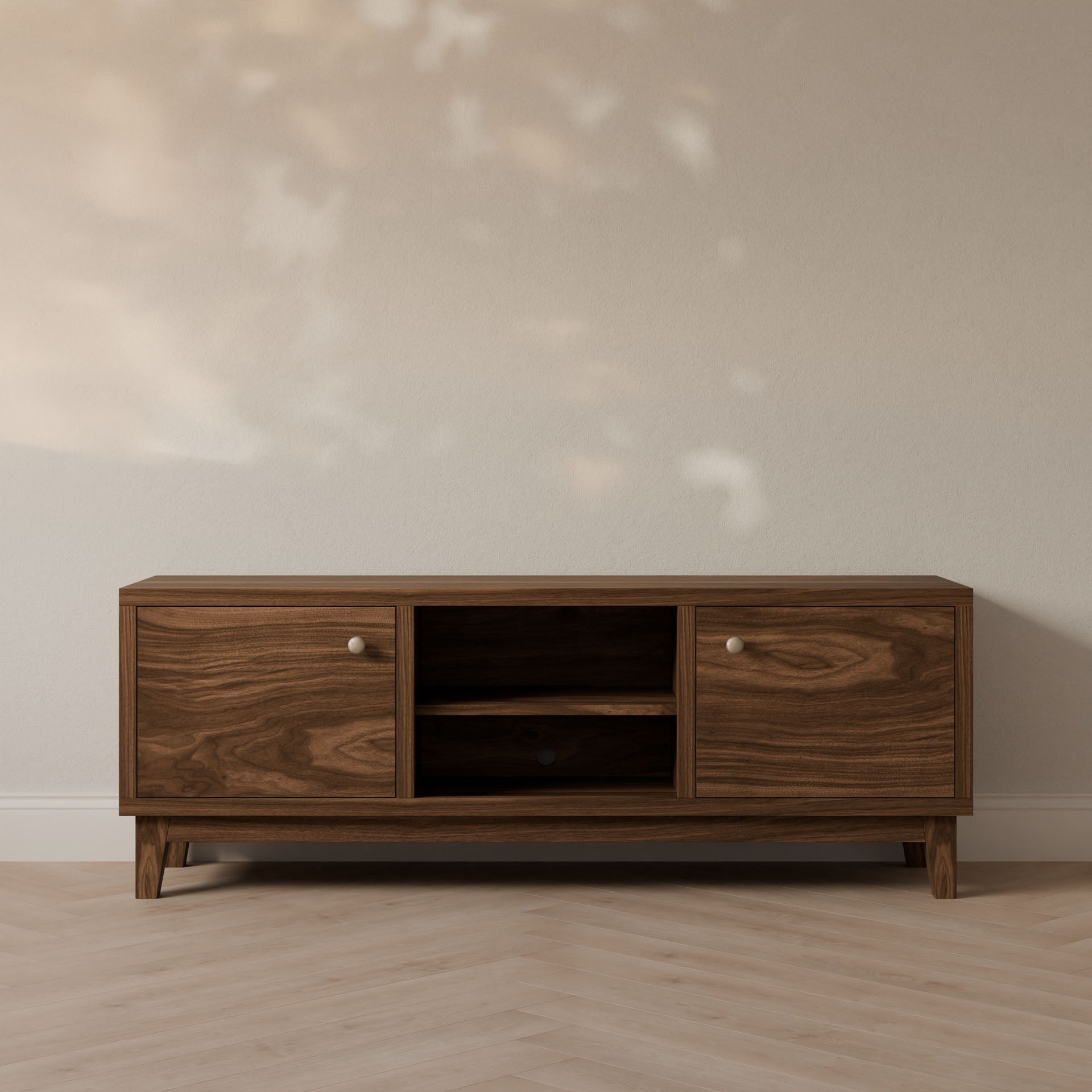 The Krovel Furniture Co. Double Door, Open Shelf Media Cabinet in Walnut features customizable side cabinets and a central open shelf, standing on short legs against a light wall with soft shadows. The floor showcases a light wood pattern.