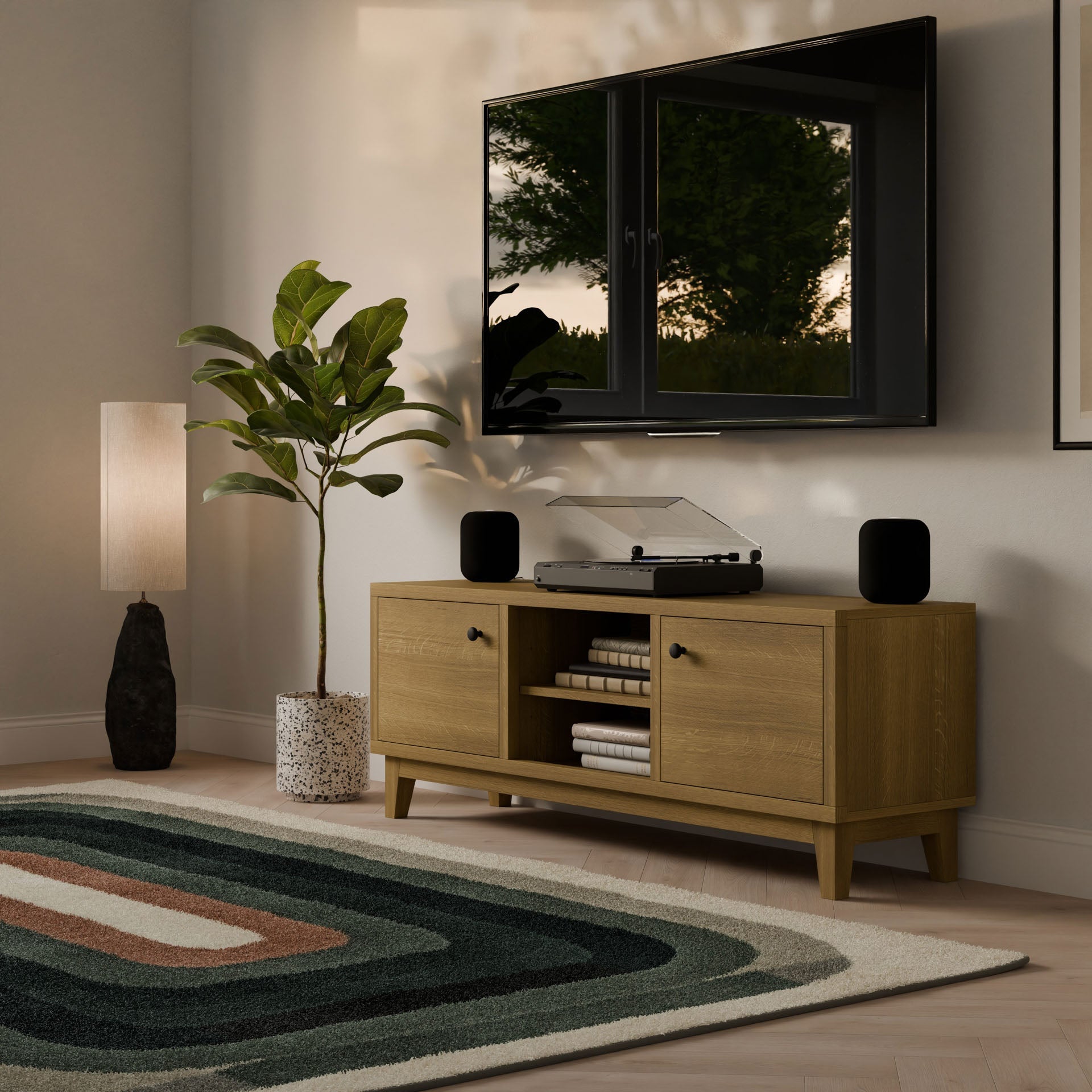 A modern living room corner features a wall-mounted TV, Krovel Furniture Co.’s Double Door, Open Shelf Media Cabinet in White Oak, a turntable and speakers, a tall lamp, a leafy potted plant, and a multicolored geometric rug on formaldehyde-free hardwood veneer flooring.