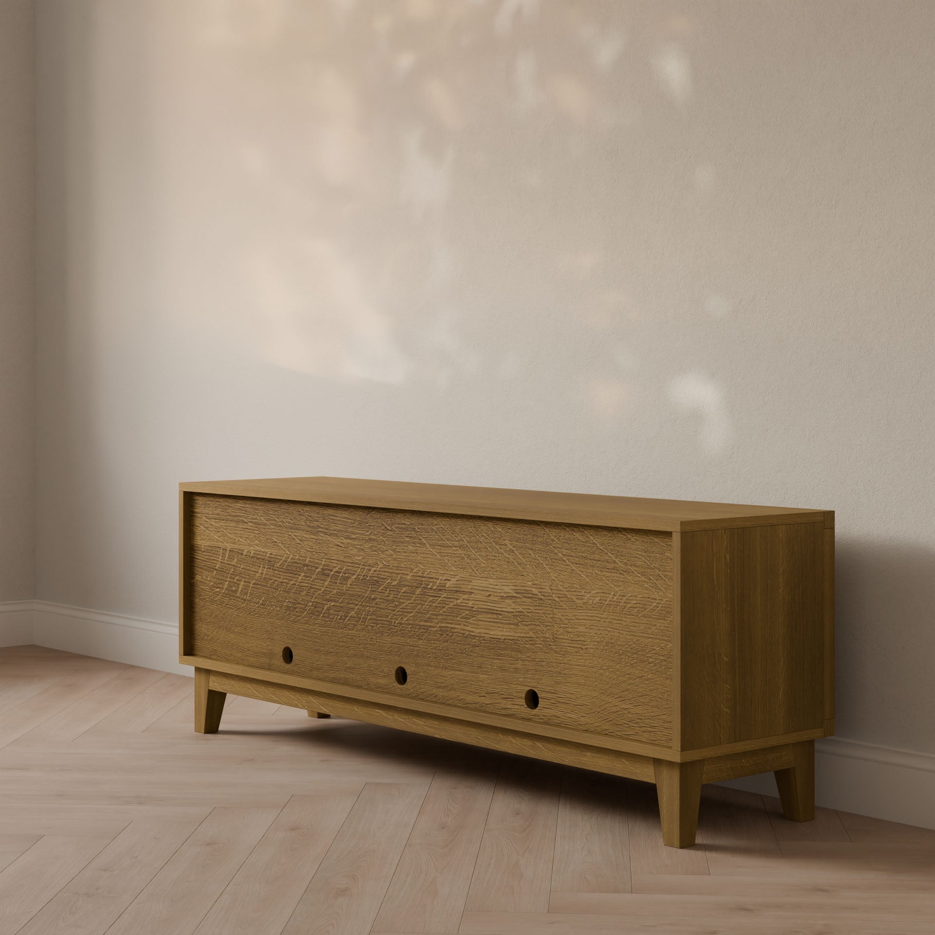 In a minimalist setting, the Double Door, Open Shelf Media Cabinet in White Oak by Krovel Furniture Co. stands on light wood flooring against a beige wall. Featuring three circular cutout handles and tapered legs, its crafted from formaldehyde-free hardwood veneer, blending seamlessly with the neutral decor.
