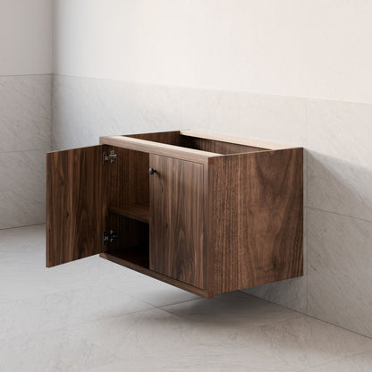 The Maine Made Double Door Vanity by Krovel Furniture Co. is a handmade, wall-mounted hardwood piece that blends functionality with minimalist design, featuring open double doors and empty interior shelves against white tiled walls and floor.