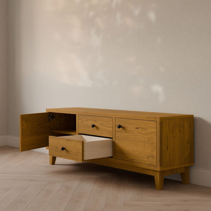The Krovel Furniture Co. Double Drawer, Double Door Media Cabinet in Cherry offers a mid-century modern design with two open-door cabinets and a pull-out drawer featuring soft-close slides. It complements light wood flooring and beige walls, casting gentle patterns.