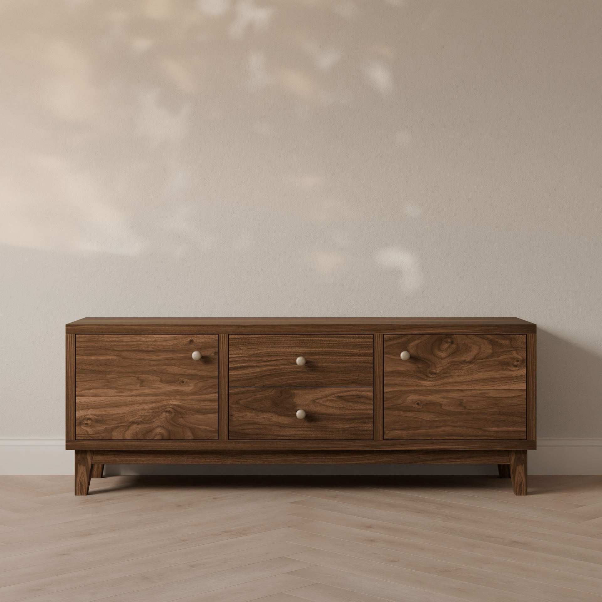 The Krovel Furniture Co. Maine Made Double Drawer, Double Door Media Cabinet stands against a light wall on a herringbone wood floor, with soft natural light casting subtle shadows on the scene.