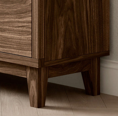 Close-up of Krovel Furniture Co.s Double Drawer, Double Door Media Cabinet in Walnut, highlighting its custom craftsmanship and rich dark brown grain. It stands on a light-colored floor with hardwood veneer against light walls.